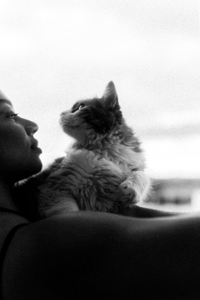 A fluffy kitten looking up beside a woman, in black and white